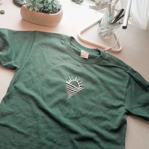 Costumed dark green shirt with embroidered sun